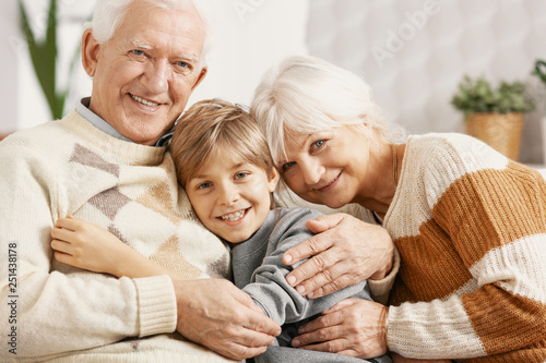 Happy grandparents hugging their grandson photo