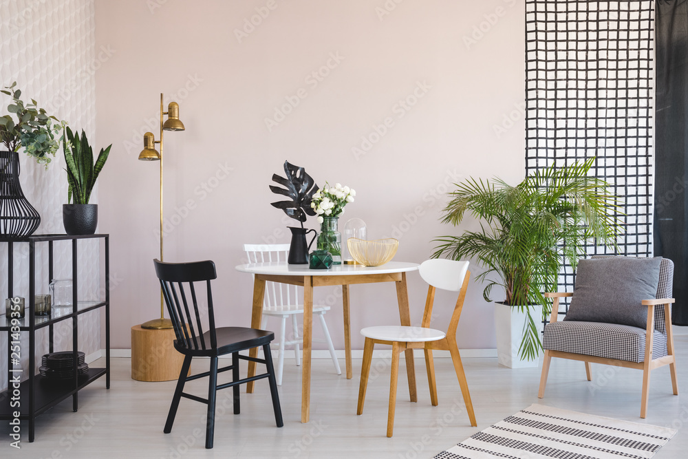 Fototapeta premium Chair at wooden table with flowers in dining room interior with armchair and gold lamp. Real photo