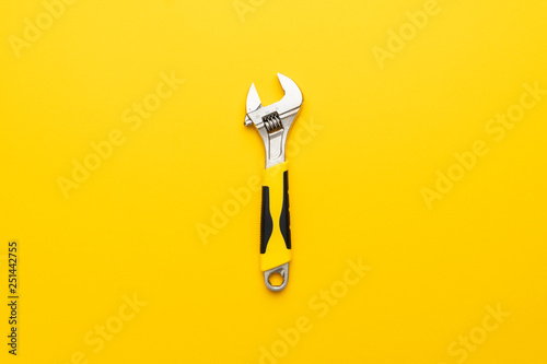 adjustable wrench with yellow handle on the yellow background photo
