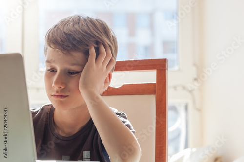 A young boy at home using a laptop to do his homework