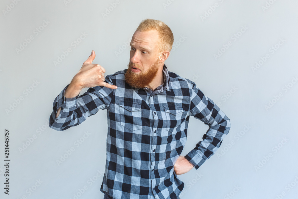 Naklejka premium Freestyle. Mature man standing isolated on grey showing call gesture confused