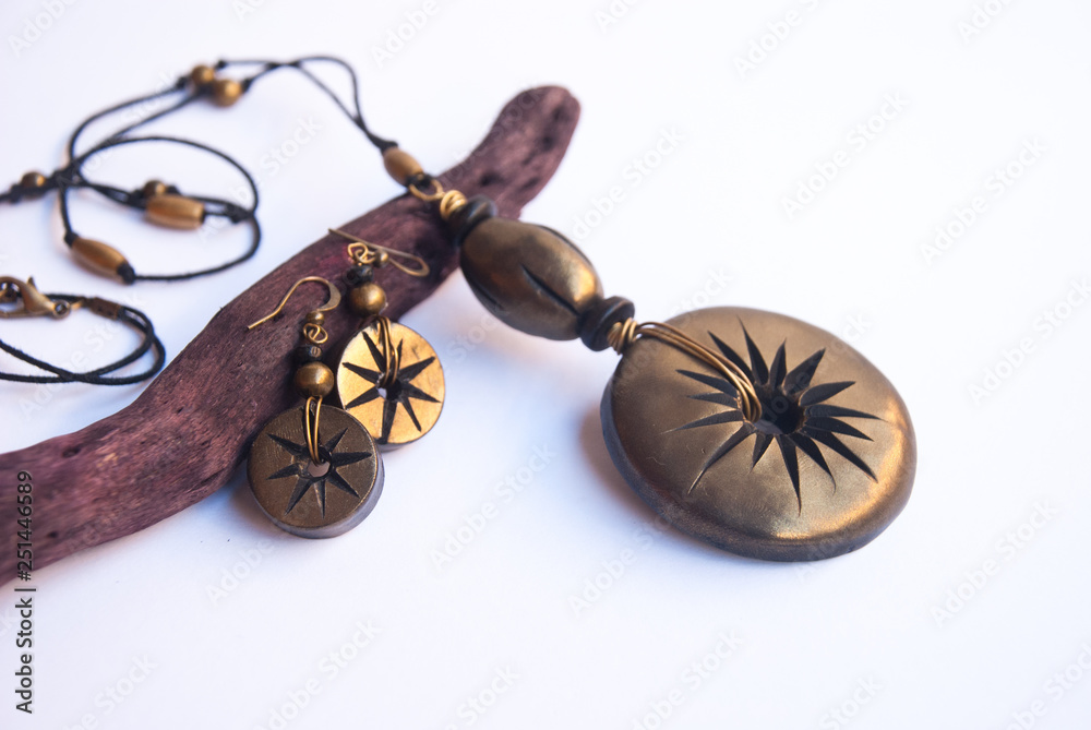 Fototapeta premium Black gold shiny boho necklace and earrings in macro. Fashion jewelry background. Handmade polymer clay jewelry.
