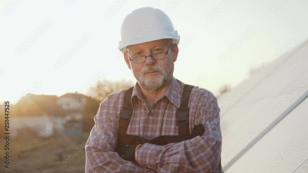 Portrait of successful engineer stands at solar batteries with crossed hands Portrait of successful engineer stands at solar batteries with crossed hands