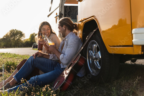 Affectionate couple on a road trip, taking a break, drinking soft drinks photo