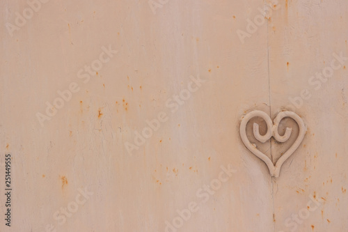 Metal heart shape on the metallic surface with rust, texture with defects