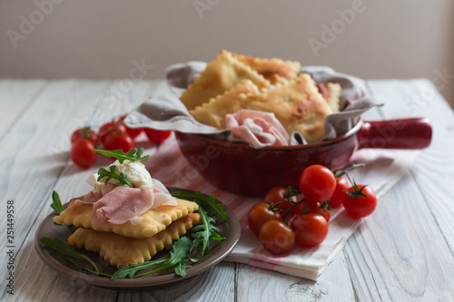 Gnocco fritto or Crescentina is a bread in Italian cuisine from the Emilia region of Italy accompanied with cheese squacquerone and prosciutto.
