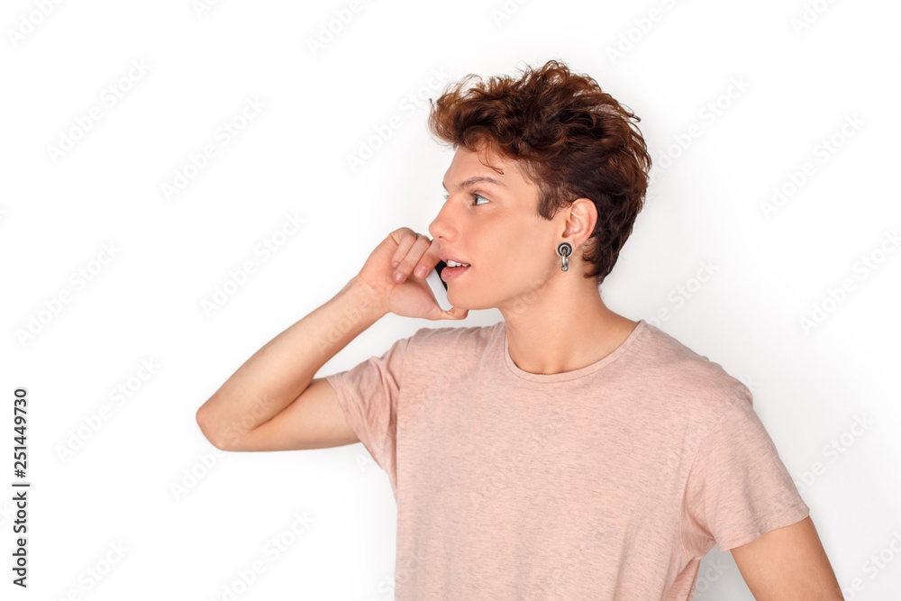 Teenager with earrings studio standing isolated on white talking on smartphone joyful side view close-up Teenager with earrings studio standing isolated on white talking on smartphone joyful side view close-up