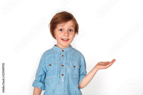 Boy studio standing isolated on grey showing space aside looking camera surprised