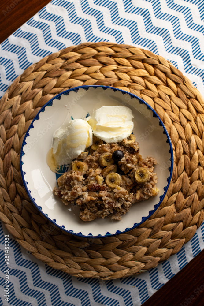 baked oatmeal with banana, blueberries, walnut and raisins. served with yoghurt and honey