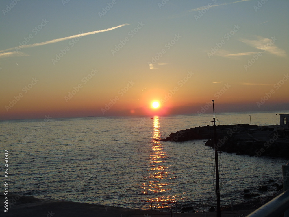 Genova, Italy - 02/14/2019: An amazing caption of the sunset over the sea and the city of Genoa in winter days and great views to the old buildings near the beach coloured by the sun Genova, Italy - 02/14/2019: An amazing caption of the sunset over the sea and the city of Genoa in winter days and great views to the old buildings near the beach coloured by the sun