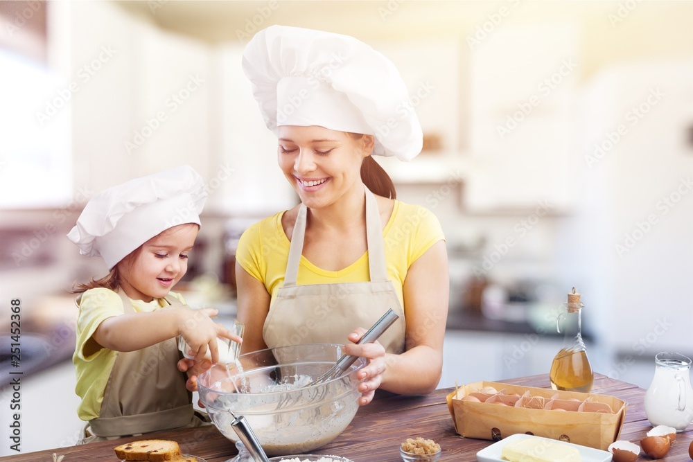 Portrait of adorable little girl and her mother baking together Portrait of adorable little girl and her mother baking together