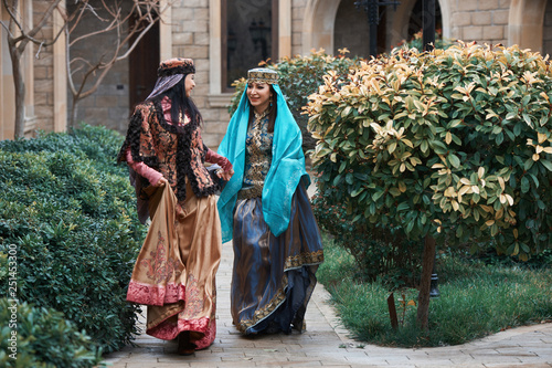 Beautiful azeri women in traditional Azerbaijani dress running by the wooden door