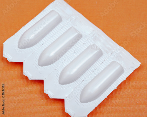 Medication in disposable plastic suppository moulds on orange background. Rectal drug administration photo