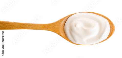 Sour cream in wooden spoon isolated on white background. Top view. Flat lay