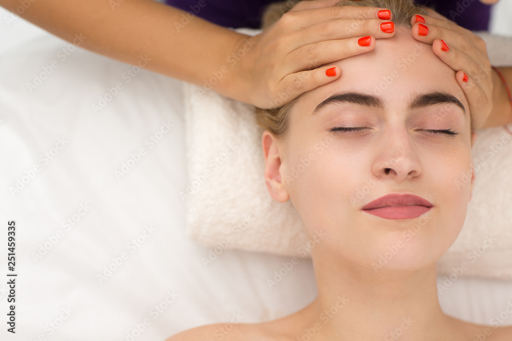 Portrait of woman face during rejuvenation procedure in spa salon. Satisfied woman with closed eyes receiving face massage, enjoying process and relaxing. Concept of beauty and pleasure.