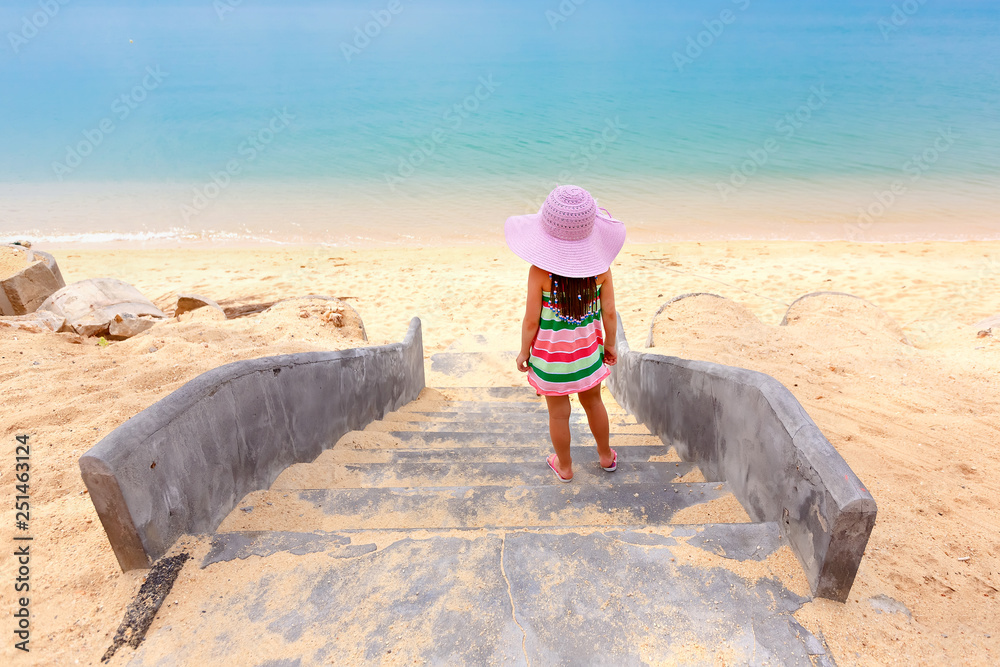 Cute girl in big hat relax ocean background. Back view of a little girl ...