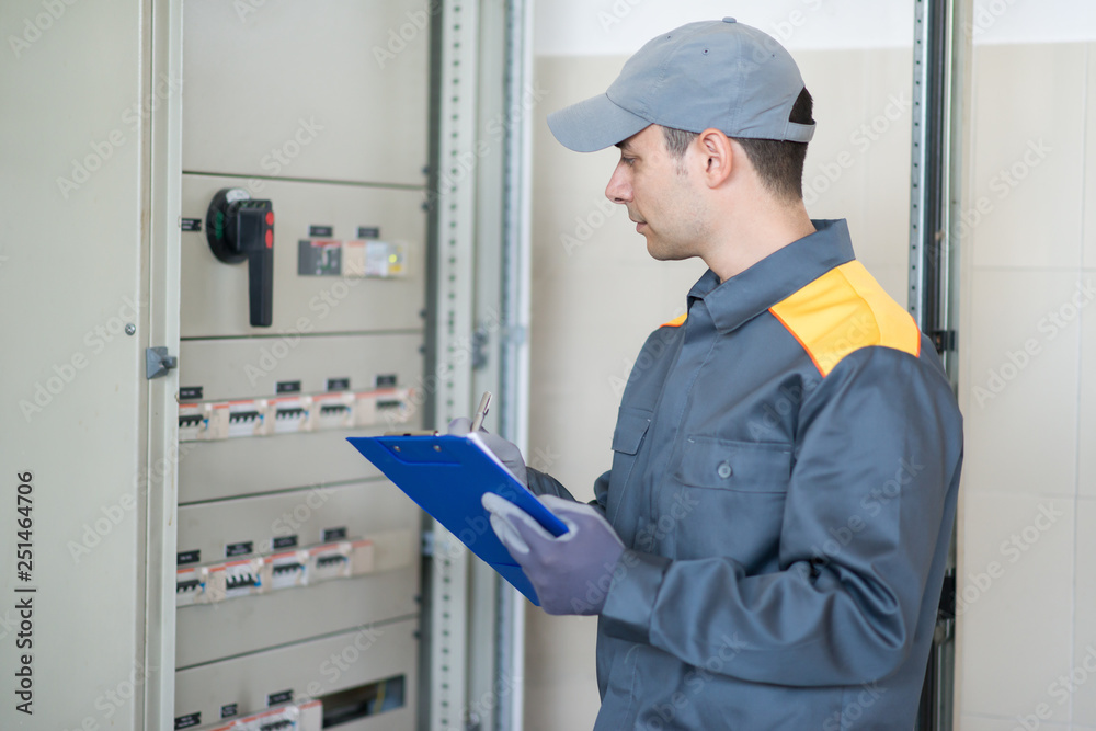 Electrician inspector checking an industrial distribution board in a factory Electrician inspector checking an industrial distribution board in a factory