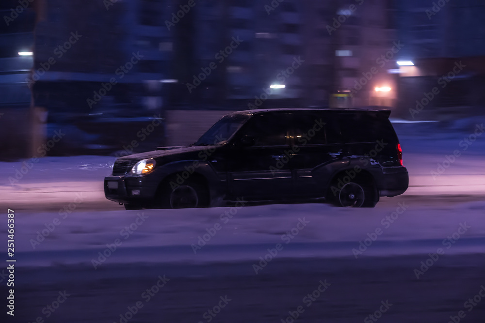 SUV moving winter night on city street