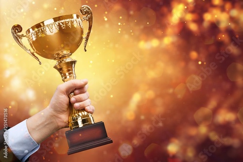 Hand of kid holding champion cup on glossy background