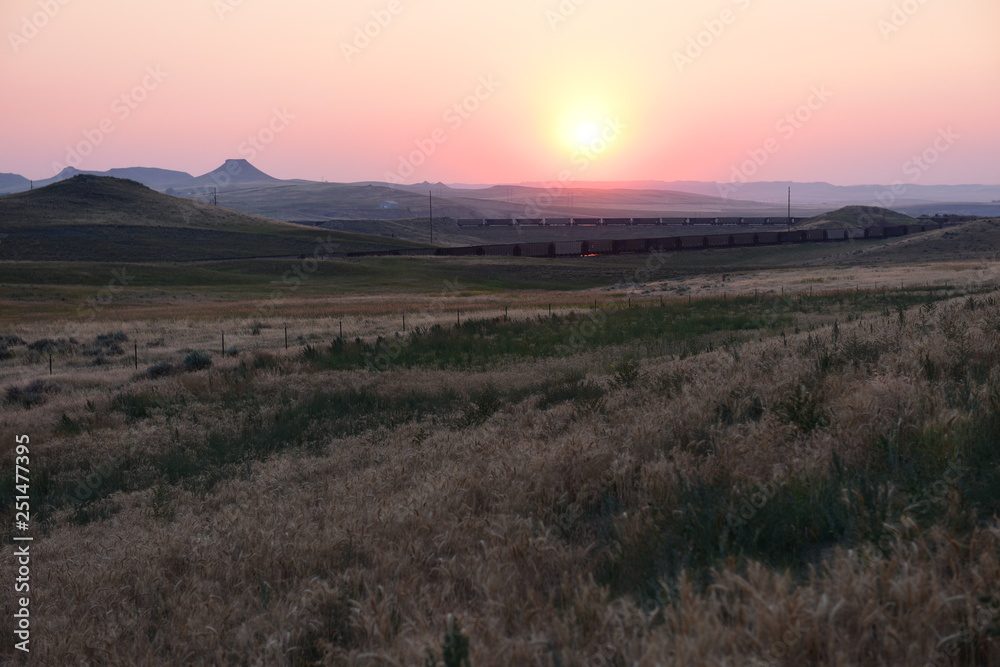 Empty high plains landscape of hills and coal train at sunset in the Powder River Basin in Wyoming, USA.