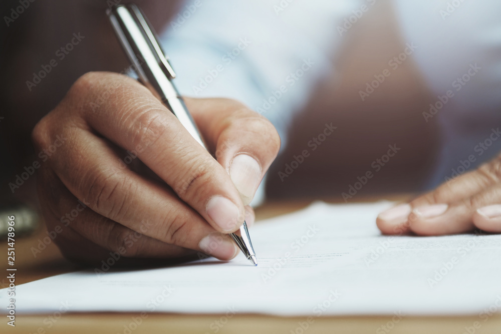 hand of woman holding pen with writing on paper report in office - obrazy, fototapety, plakaty 