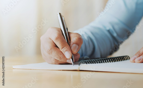 hand of woman holding pen with writing on notebook in office photo
