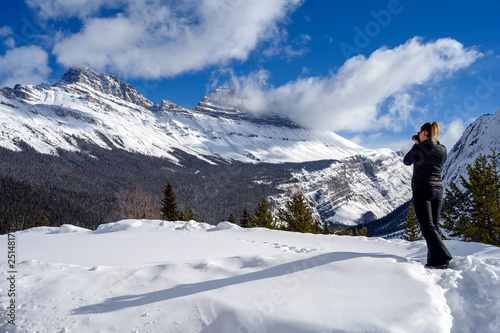 Female nature photographer taking picture of the snowy mountains at the Icefields Parkway in Jasper National, Alberta, Canada