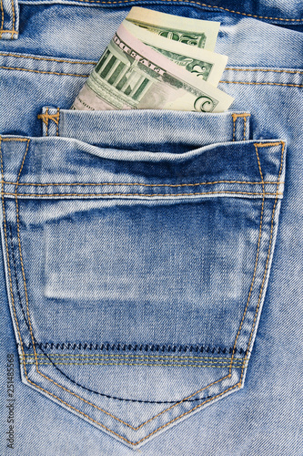 Paper banknotes us dollars in the pocket of blue jeans. Denim backgrounds.