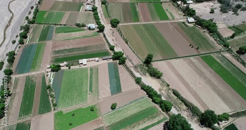 Top aerial drone scene of small local crops with rocky meandric river limiting at the side. Abstract natural green checkerboard shape, Maimara, Jujuy, Argentina
