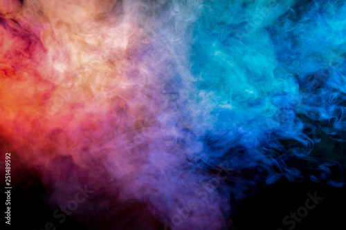 Translucent, thick smoke, illuminated by light against a dark background, divided into three colors: blue, green, pink and purple, burns out, evaporating from a steam of vape for print on t-shirt
