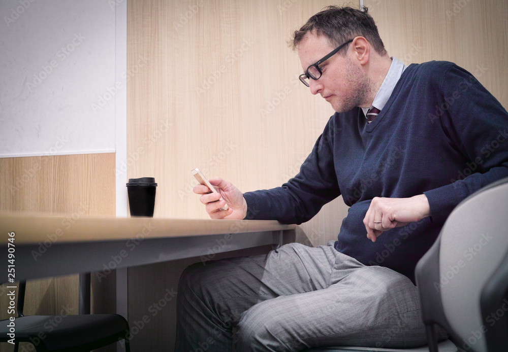 A man looking at his phone while killing time in his break