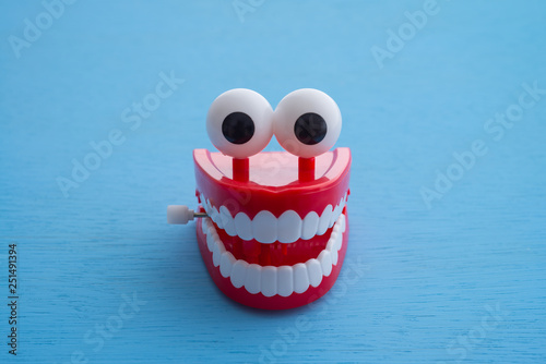 Chattering teeth toy wind up moving on blue background. Funny, comedy, relax time concept photo