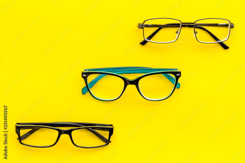 Set of glasses with transparent lenses on yellow background top view copy space Set of glasses with transparent lenses on yellow background top view copy space