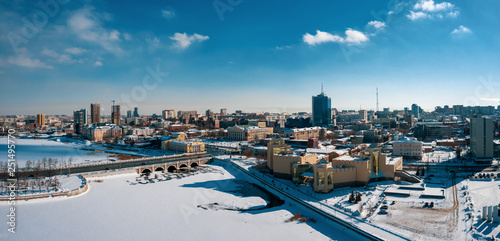 Aerial drone panorama; beautiful view Chelyabinsk city with white snowy streets and bridges; sunny winter day in South Ural capital; industrial and pollution problem; undeveloped urban environment
