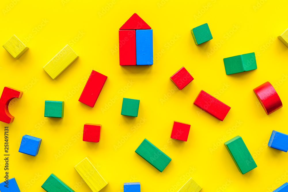 Children background. Wooden building blocks for developing and entertainment on yellow background top view
