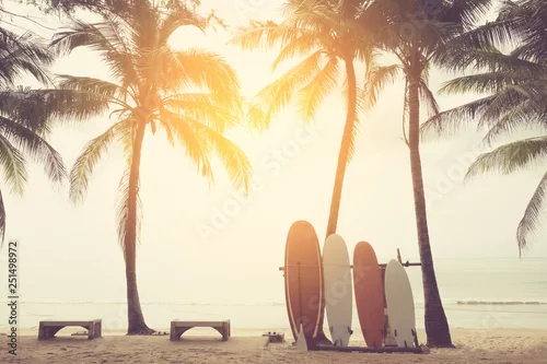 Obraz Deska surfingowa i palmy na tle plaży.