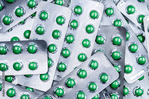 Closeup pile of round green sugar coated tablet pill in blister pack. Combine pill for relief cough. Pharmaceutical product. Pharmaceutical industry. Pharmacy background. Medicine for dry cough. photo