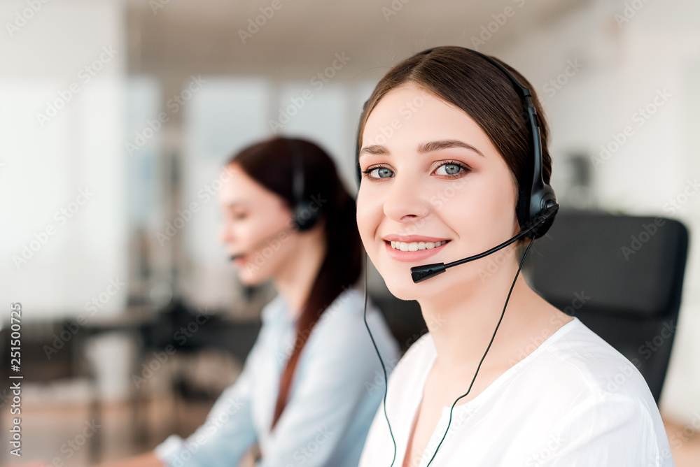 Friendly young female technical support dispatcher with a headset working in a call center on a hotline, talking on the phone. Portrait of an attractive customer care representative. Business concept Friendly young female technical support dispatcher with a headset working in a call center on a hotline, talking on the phone. Portrait of an attractive customer care representative. Business concept