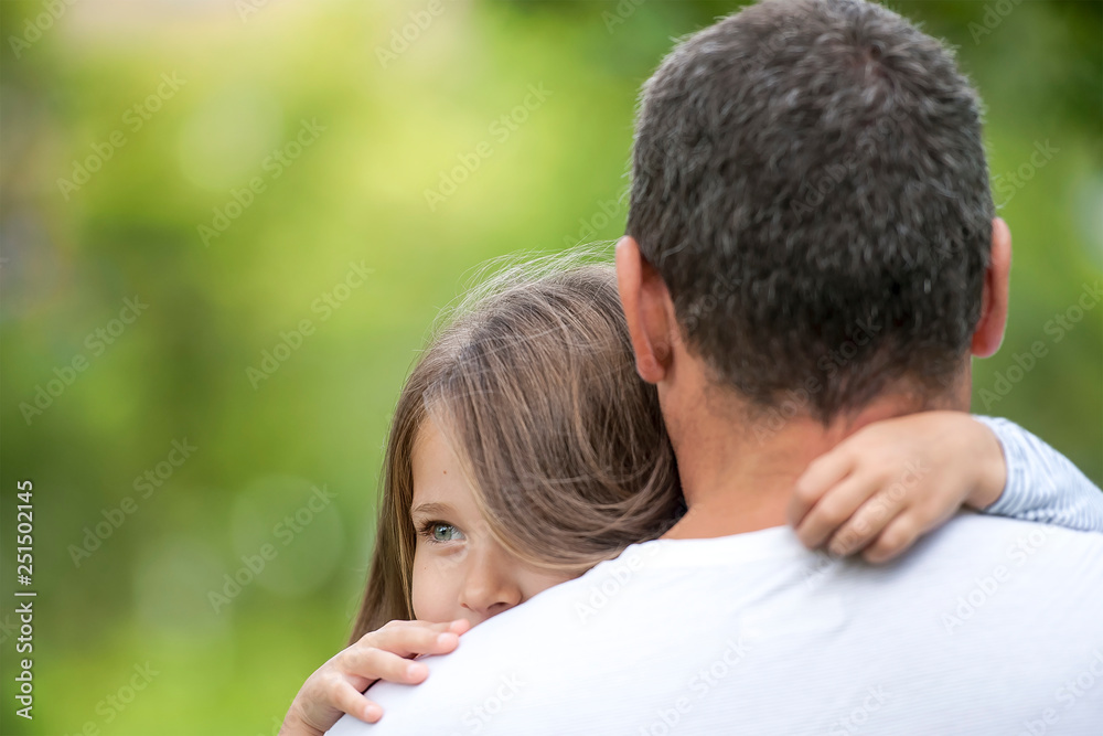 Girl hugging her father. Happy loving family. Dad and his daughter playing. Cute baby and daddy. Concept of Father day. Family holiday and togetherness. Green background