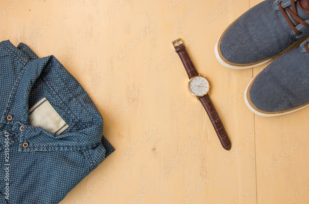 Men's casual outfits with jeans clothes and accessories on a wooden light background, the concept of fashion and beauty, flat beds