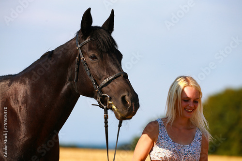 Horse with owner in portrait on a summer field, owner cuddles with her horse. © RD-Fotografie