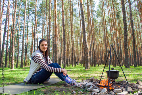 Young woman in the woods near the fire with a pot photo