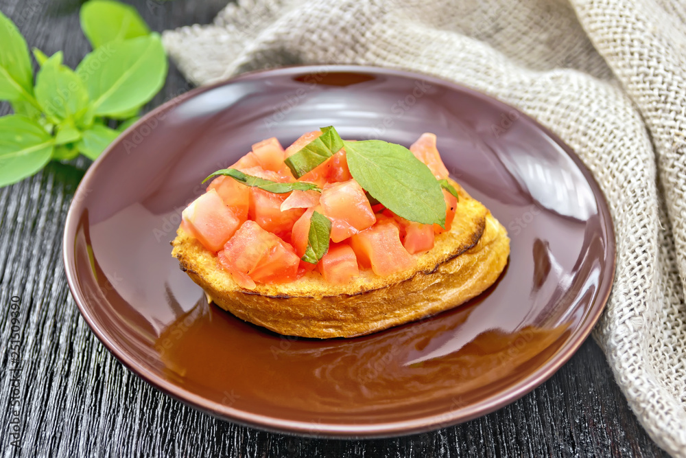 Bruschetta with tomato and basil in brown plate on dark board Bruschetta with tomato and basil in brown plate on dark board
