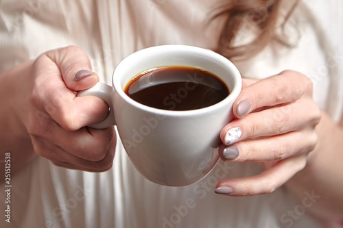 Female hands holding white cup of black coffee, closeup