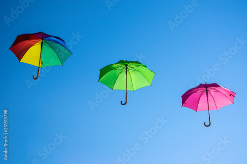Group of flying umbrellas isolated on blue background  ready for the rain  wallpaper background  bright various colors