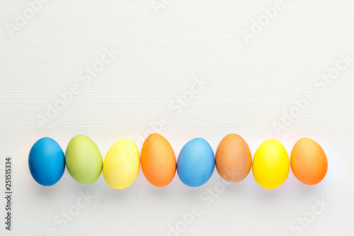 Bright easter eggs on white wooden background, top-view