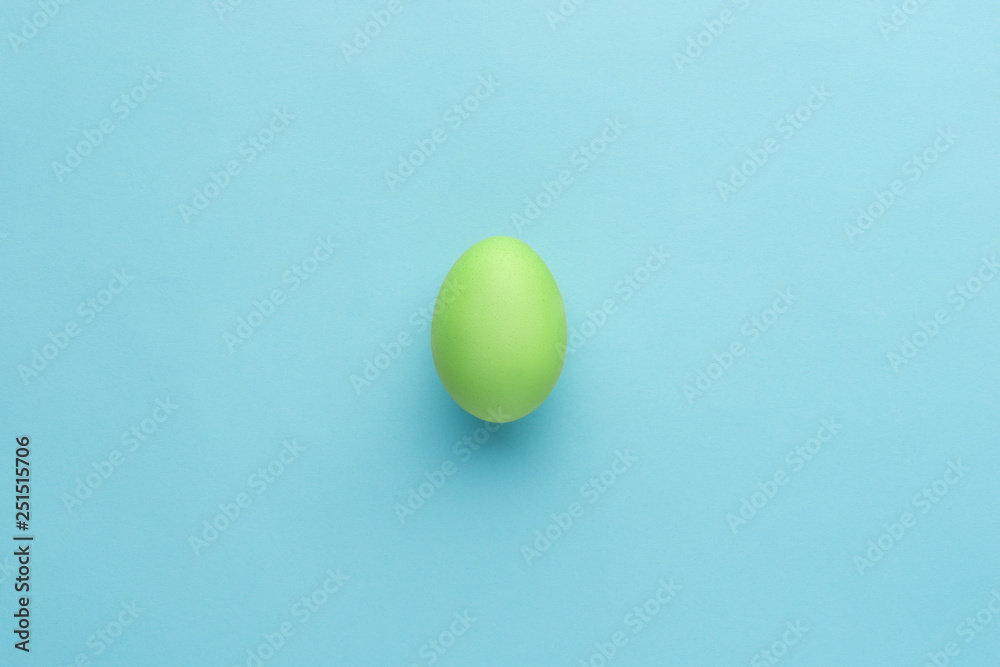 Painted green egg on blue background