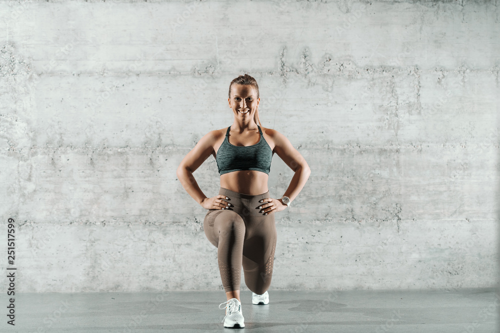 Φωτογραφία Smiling Caucasian sporty woman dressed in sportswear and with ponytail doing lunges in the gym