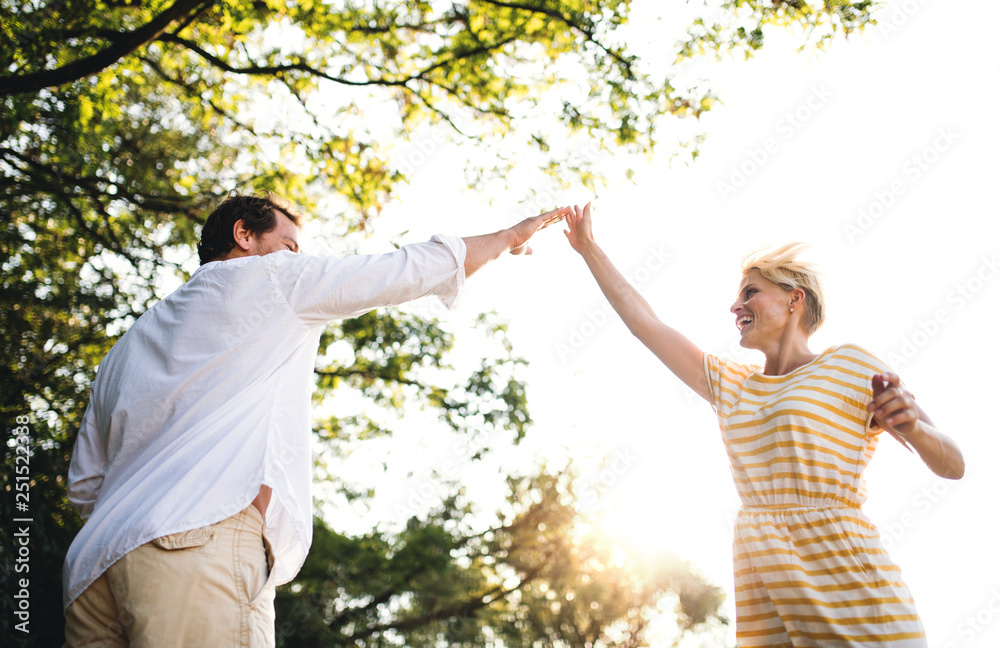 A young couple spending time together in nature in summer, making high five.