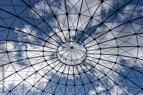 Bottom view of an iron structure with blue sky and clouds in the background